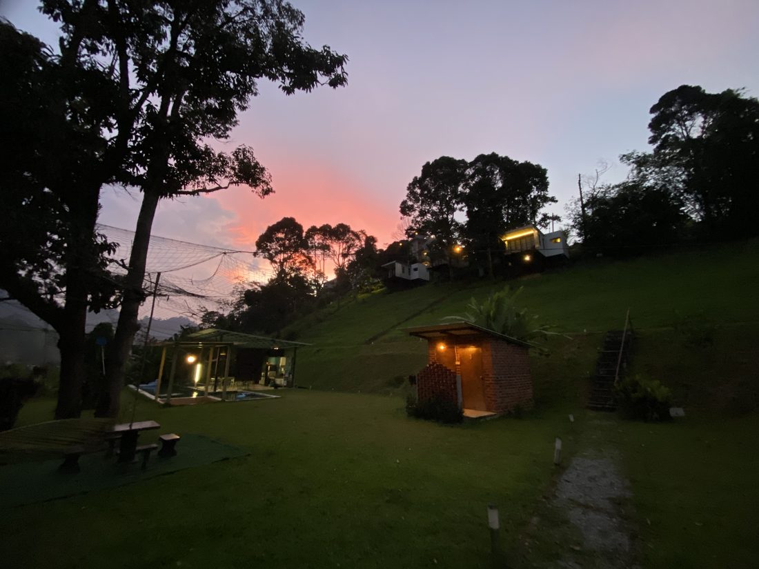 The pool house and a small brick shed lit up as the sky turns pink at dusk