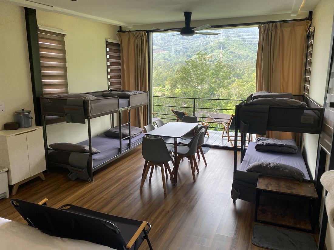 A shared dining table for six inside the chalet, with the balcony and hills beyond