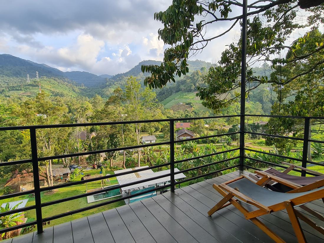 The balcony by day: two deck chairs facing the forested valley, with the pool visible below