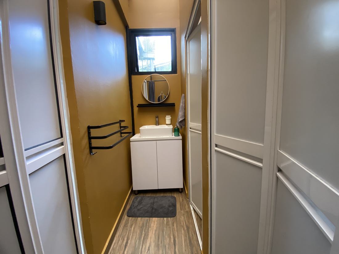 The attached bathroom: a vessel sink, round mirror and separate sliding-door shower, lit by a window