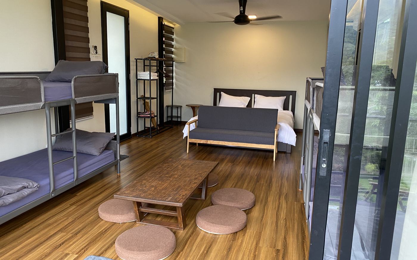Inside Chalet 3: bunk beds on the left, a king bed and sofa, and a low tatami table with floor cushions in the foreground