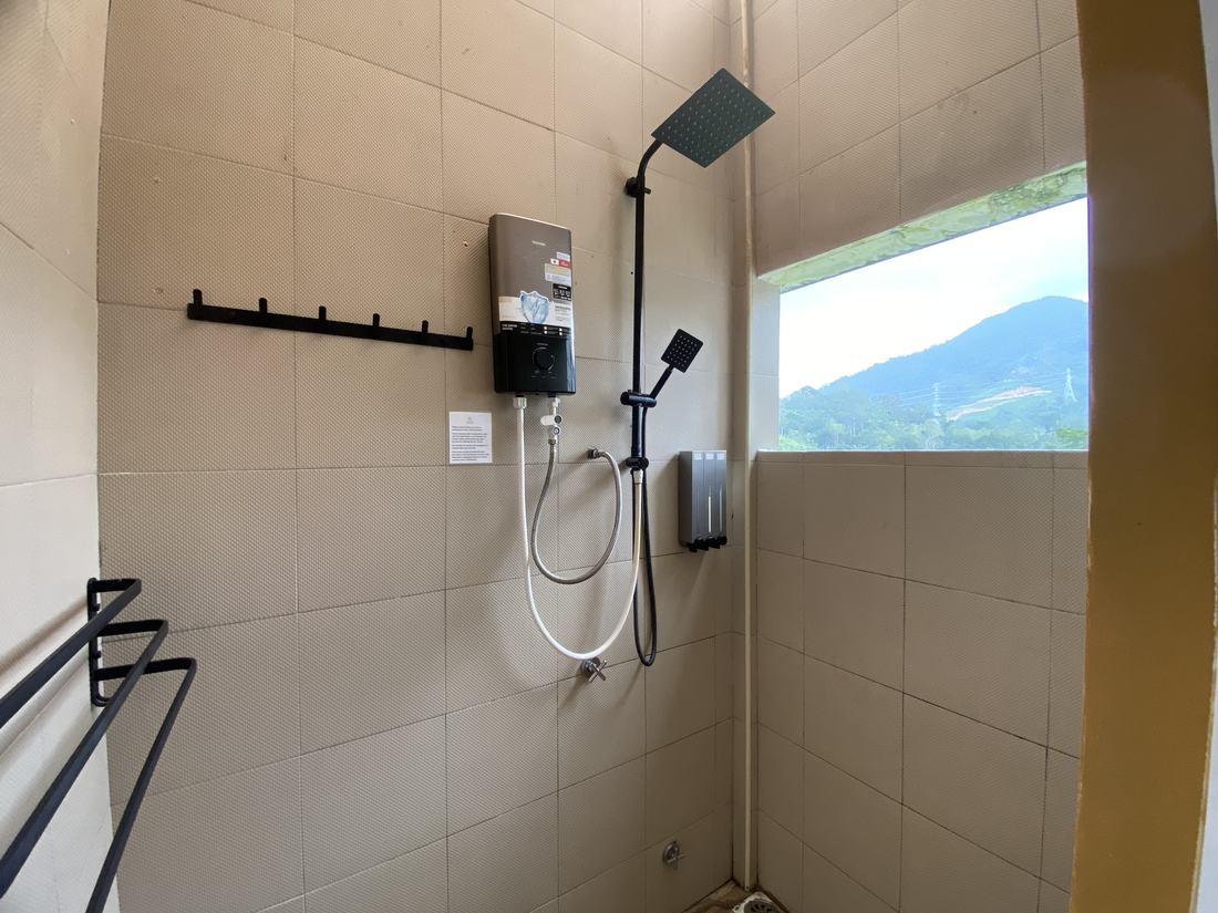 The shower, with a window looking straight out at the forested hills